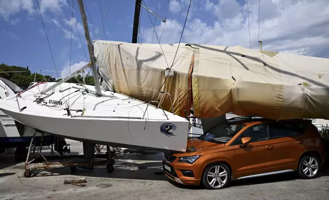 A car and boats are damaged in Split, Croatia, Tuesday, July 8, 2025, following a powerful storm. (AP Photo/Tom Dubravec)
