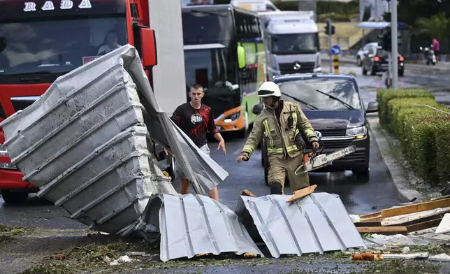 A fireman removes debris from a street in Split, Croatia, Tuesday, July 8, 2025, following a powerful storm. (AP Photo/Tom Dubravec)