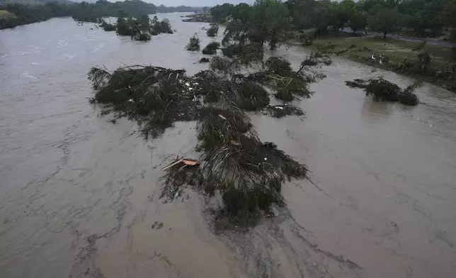 A raging Guadalupe River leaves fallen trees and debris in its wake, Friday, July 4, 2025, in Kerrville, Texas. (AP Photo/Eric Gay)