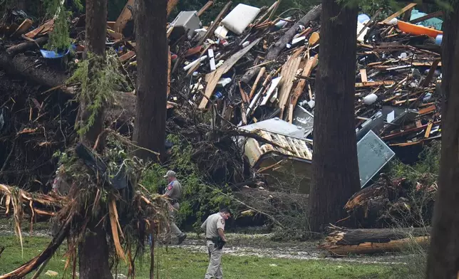 Officials comb through the banks of the Guadalupe River after a flash flood swept through the area Saturday, July 5, 2025, in Hunt, Texas. (AP Photo/Julio Cortez)