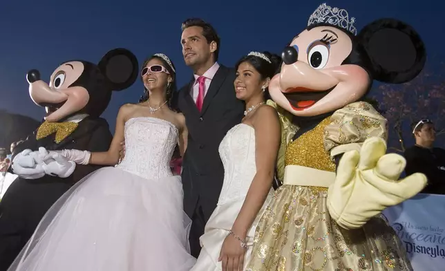 FILE - Actor Cristian de la Fuente, center, poses for photos with Shalmary Arroyo, left, Amethist Martinez, right, and Mickey and Minnie Mouse on the red carpet as 15 young ladies from across the United States and Puerto Rico were given an opportunity celebrate their Quinceañera at Disneyland Resort in Anaheim, Calif., April 24, 2008. (AP Photo/Mark Avery, File)