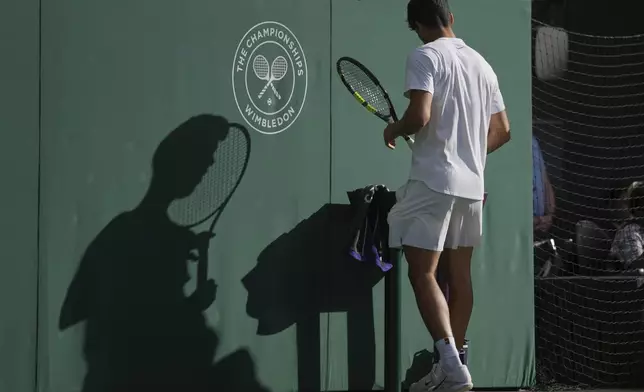 The shadow of Carlos Alcaraz of Spain is reflected on the back wall as he plays Jan-Lennard Struff of Germany during a third round men's singles match at the Wimbledon Tennis Championships in London, Friday, July 4, 2025. (AP Photo/Kin Cheung)