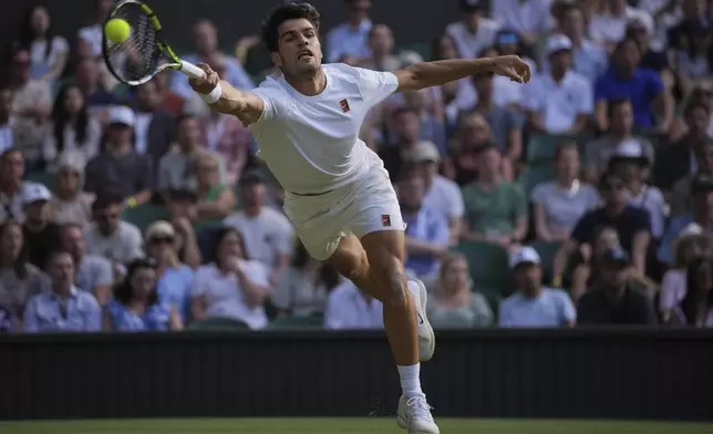 Carlos Alcaraz of Spain stretches to return to Jan-Lennard Struff of Germany during a third round men's singles match at the Wimbledon Tennis Championships in London, Friday, July 4, 2025. (AP Photo/Kin Cheung)