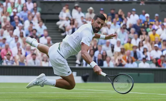 Novak Djokovic of Serbia dives to return to Miomir Kecmanovic of Serbia during a third round men's singles match at the Wimbledon Tennis Championships in London, Saturday, July 5, 2025. (AP Photo/Kirsty Wigglesworth)