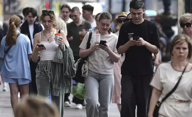Pedestrians look at their phones while walking through St. Petersburg, Russia, on Monday, July 14, 2025. (AP Photo/Dmitri Lovetsky)