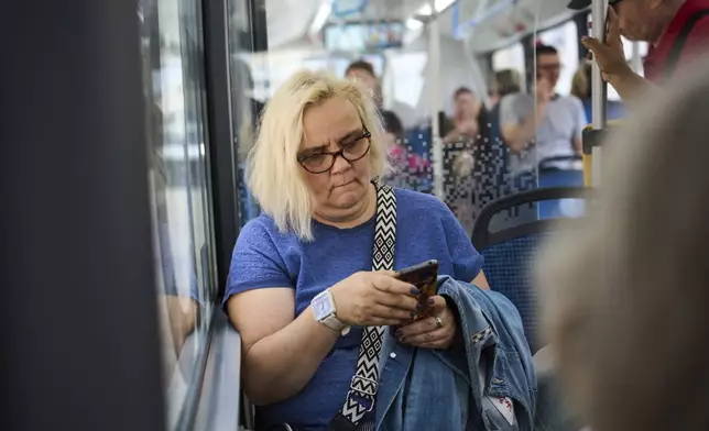 A woman riding a bus looks at her phone in Moscow on Wednesday, July 16, 2025. (AP Photo/Alexander Zemlianichenko)