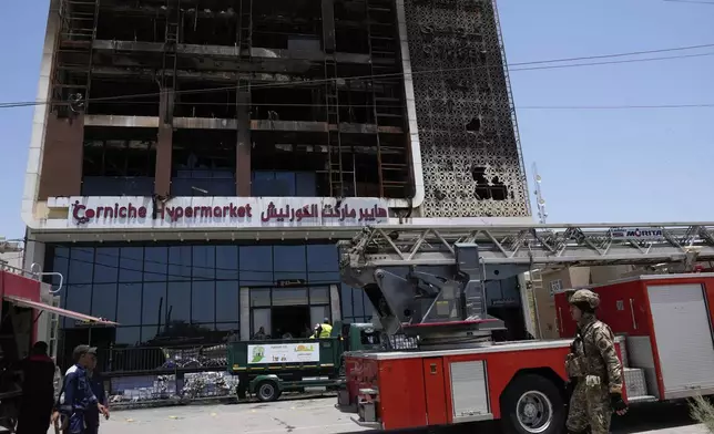 Firefighters gather in front of a burning hypermarket building in Kut, Iraq, Thursday, July 17, 2025. (AP Photo/ Hadi Mizban)