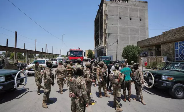 Iraqi security forces gather in front of a burning hypermarket building in Kut, Iraq, Thursday, July 17, 2025. (AP Photo/Hadi Mizban)