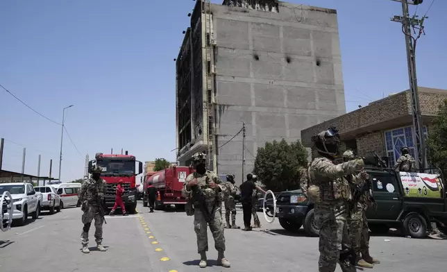 Iraqi Security forces gather in front of a burning hypermarket building in Kut, Iraq, Thursday, July 17, 2025. (AP Photo/Hadi Mizban)
