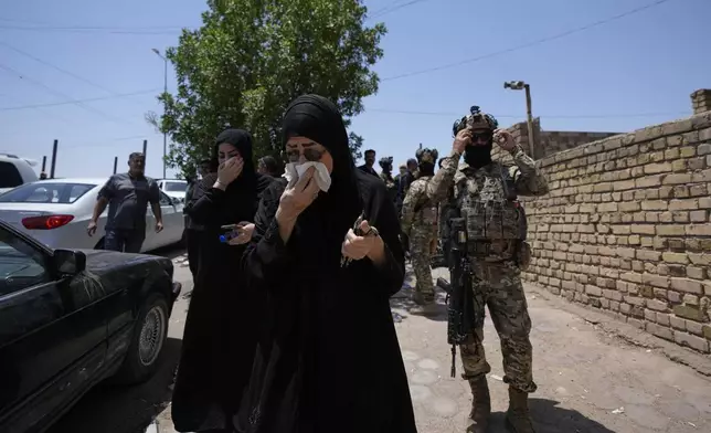 Iraqi people gather in front of a burning hypermarket building in Kut, Iraq, Thursday, July 17, 2025. (AP Photo/ Hadi Mizban)
