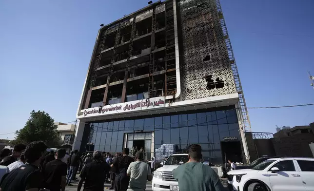Iraqi people gather in front of a burning hypermarket building in Kut, Iraq, Thursday, July 17, 2025. (AP Photo/Hadi Mizban)