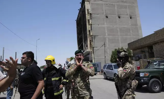 Iraqi security forces gather in front of a burning hypermarket building in Kut, Iraq, Thursday, July 17, 2025. (AP Photo/ Hadi Mizban)