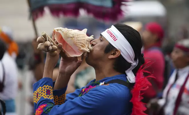 A dancer dressed in Indigenous clothing blows on a conch shell marking the 700th anniversary of the founding of Tenochtitlan, known today as Mexico City, in the capital's main square, the Zocalo, Saturday, July 26, 2025. (AP Photo/Eduardo Verdugo)