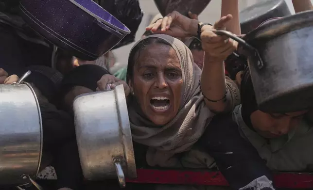 Palestinians struggle to get donated food at a community kitchen, in Gaza City, northern Gaza Strip, Saturday, July 26, 2025. (AP Photo/Abdel Kareem Hana)