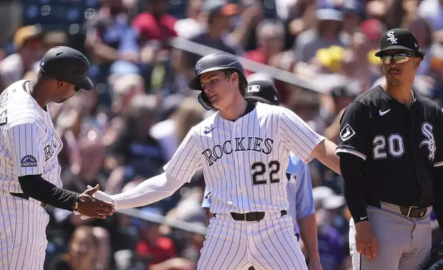 Colorado Rockies third base coach Andy González, left, congratulates Mickey Moniak after his triple to drive in two runs as Chicago White Sox third baseman Miguel Vargas, right, looks on in the fifth inning of a baseball game Sunday, July 6, 2025, in Denver. (AP Photo/David Zalubowski)