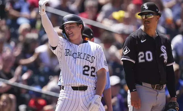 Colorado Rockies' Mickey Moniak, left, gestures to the dugout after reaching third base on a triple to drive in two runs as Chicago White Sox third baseman Miguel Vargas looks on in the fifth inning of a baseball game, Sunday, July 6, 2025, in Denver. (AP Photo/David Zalubowski)