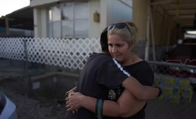 Erika Sarabia is hugged by her son, Gustavo Chavez, outside their mobile home during a meeting with community outreach program coordinators in Oasis, Calif., Monday, April 14, 2025. (AP Photo/Jae C. Hong)