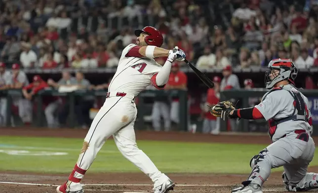 Arizona Diamondbacks' Eugenio Suárez, left, watches the flight of his three-run home run as St. Louis Cardinals catcher Yohel Pozo, right, looks on during the first inning of a baseball game Sunday, July 20, 2025, in Phoenix. (AP Photo/Ross D. Franklin)