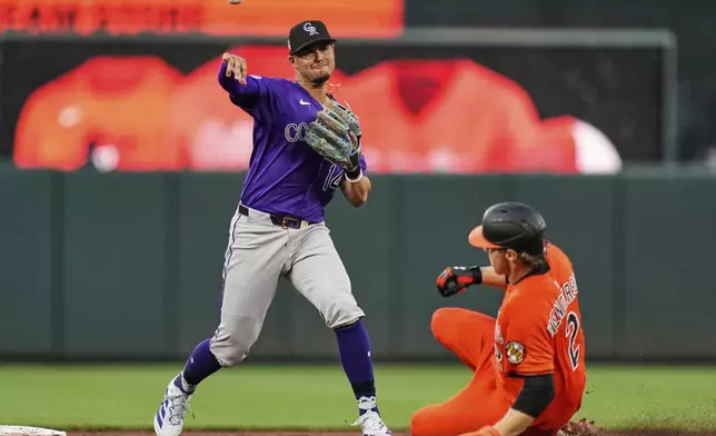 Colorado Rockies shortstop Ezequiel Tovar (14) turns a double play as Baltimore Orioles' Gunnar Henderson (2) is forced out at second base during the third inning of a baseball game, Saturday, July 26, 2025, in Baltimore. (AP Photo/Stephanie Scarbrough)