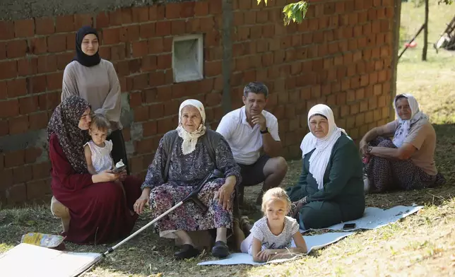 Bosnian Muslim family watch people participating in the "March of Peace" in memory of the 1995 Srebrenica massacre, in Nezuk, Bosnia, Tuesday, July 8, 2025. (AP Photo/Armin Durgut)