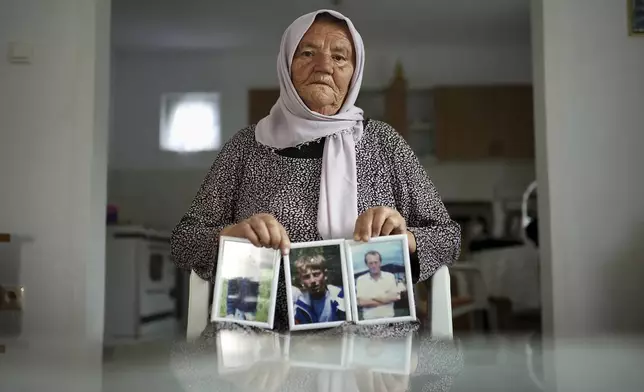 Saliha Osmanovic, 71, poses for a photo while holding pictures of her two sons and husband, victims of the Srebrenica genocide in the village of Dobrak near Srebrenica, Bosnia, on June 28, 2025. During the genocide a total of 38 members of her family were killed. (AP Photo/Armin Durgut)