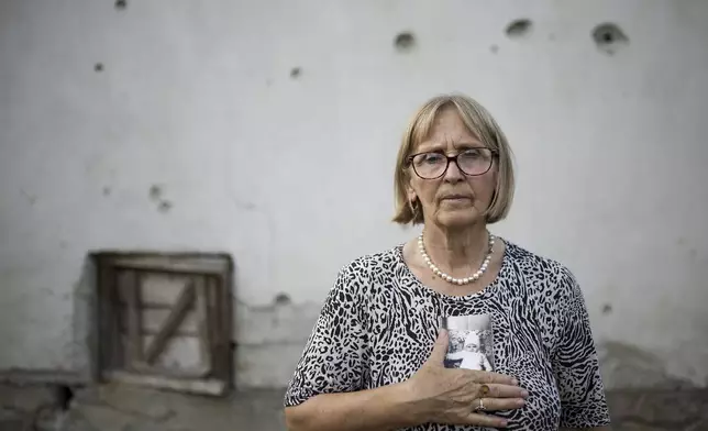 Sehida Abdurahmanovic, 74, poses for a photo while holding pictures of family members, victims of the Srebrenica genocide in village of Potocari near Srebrenica, Bosnia, on June 28, 2025. Body of her brother was never found. (AP Photo/Armin Durgut)