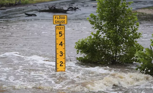 A flood gauge marks the height of water flowing over a farm-to-market road near Kerrville, Texas, on Friday, July 4, 2025. (AP Photo/Eric Gay)