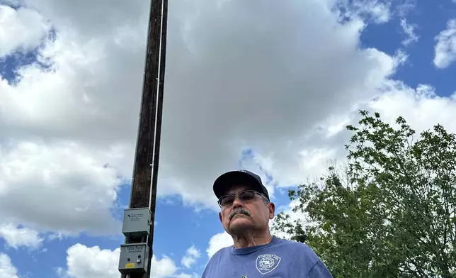 Comfort, Texas, Assistant Fire Chief, Danny Morales stands under a flash flood siren in the community's park on Thursday, July 10, 2025. (AP Photo/Sean Murphy)