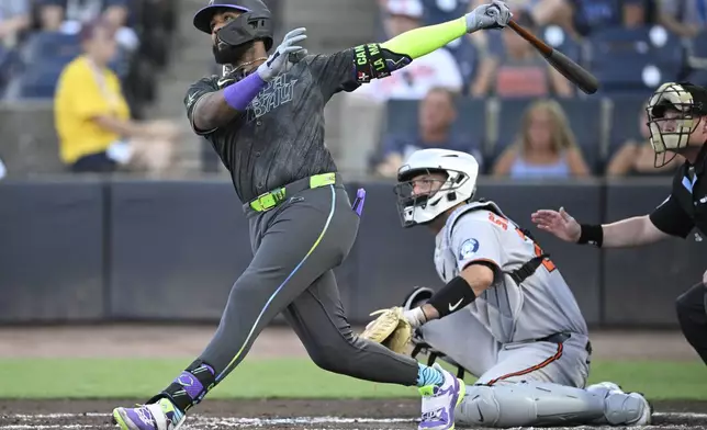 Tampa Bay Rays' Junior Caminero, left, watches the flight of the ball after hitting a three-run home run as Baltimore Orioles catcher Jacob Stallings and home plate umpire Sean Barber, right, look on during the first inning of a baseball game, Friday, July 18, 2025, in Tampa, Fla. (AP Photo/Phelan M. Ebenhack)