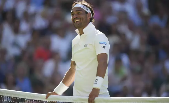 Fabio Fognini of Italy smiles after touching the net and losing the point as he plays Carlos Alcaraz of Spain during their first round men's singles match at the Wimbledon Tennis Championships in London, Monday, June 30, 2025. (AP Photo/Alastair Grant)