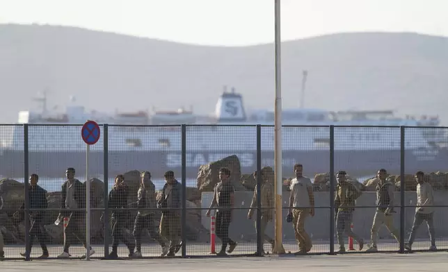 Migrants rescued south of Crete walk after their arrival at the the port of Lavrio, Greece, on Thursday, July 10, 2025. (AP Photo/Petros Giannakouris)