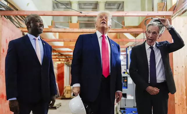 Federal Reserve Chairman Jerome Powell, right, takes off his hard hat as President Donald Trump, center, and Sen. Tim Scott, R-S.C., look at ongoing construction at the Federal Reserve, Thursday, July 24, 2025, in Washington. (AP Photo/Julia Demaree Nikhinson)