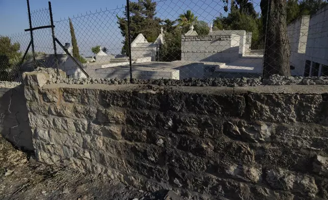 Char marks Palestinians say are from an attack by Israeli settlers are visible in the cemetery nearby the Saint George Greek Orthodox Church in the West Bank village of Taybeh, Monday, July 14, 2025. (AP Photo/Nasser Nasser)