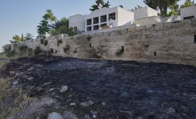 Char marks Palestinians say are from an attack by Israeli settlers are visible in the cemetery nearby the Saint George Greek Orthodox Church in the West Bank village of Taybeh, Monday, July 14, 2025. (AP Photo/Nasser Nasser)