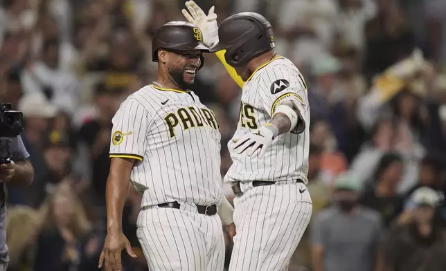 San Diego Padres' Manny Machado, right, celebrates with teammate Elias Diaz after hitting a three-run home run during the seventh inning of a baseball game against the New York Mets Tuesday, July 29, 2025, in San Diego. (AP Photo/Gregory Bull)