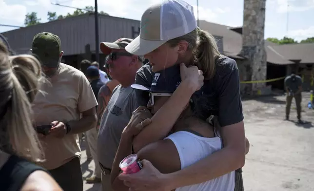 Volunteers helping in search and recovery efforts embrace during a press conference on Tuesday, July 8, 2025, in Hunt, Texas. (AP Photo/Eli Hartman)