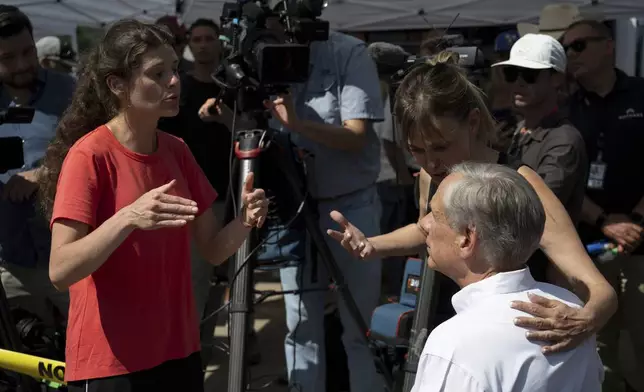 Courtney Calhoun, a resident in Kerr County, left, and Renee DeRese, top right, confront Texas Gov. Greg Abbott on Tuesday, July 8, 2025, in Hunt, Texas. (AP Photo/Eli Hartman)