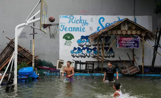Boys play basketball at a flooded court as Typhoon Co-may intensified seasonal monsoon rains at Malabon city, Philippines on Friday, July 25, 2025. (AP Photo/Aaron Favila)