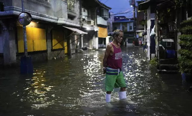 A man walks along a flooded road as intense rains continue due to the southwest monsoon at Malabon city, Philippines on Thursday, July 24, 2025. (AP Photo/Aaron Favila)