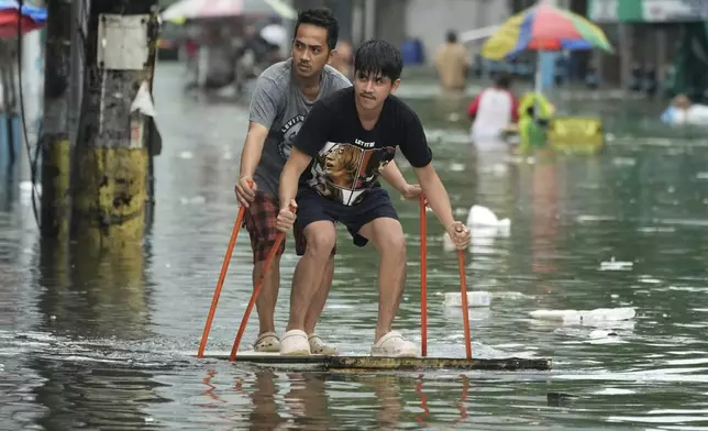 Residents use poles as they ride an improvised float along a flooded road as Typhoon Co-may intensified seasonal monsoon rains at Malabon city, Philippines on Friday, July 25, 2025. (AP Photo/Aaron Favila)