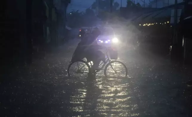 A man pedals his bicycle along a flooded road as intense rains continue due to the southwest monsoon at Malabon city, Philippines on Thursday, July 24, 2025. (AP Photo/Aaron Favila)