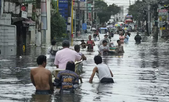Residents wade along a flooded road as Typhoon Co-may intensified seasonal monsoon rains at Malabon city, Philippines on Friday, July 25, 2025. (AP Photo/Aaron Favila)