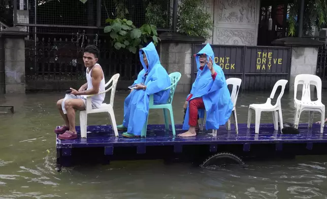 Residents ride a cart along a flooded road as Typhoon Co-may intensified seasonal monsoon rains at Malabon city, Philippines on Friday, July 25, 2025. (AP Photo/Aaron Favila)