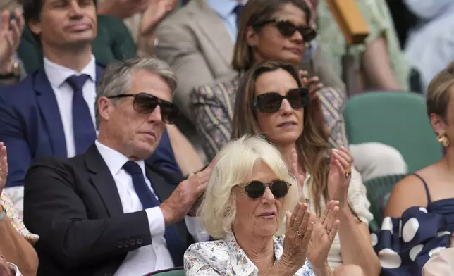 Britain's Queen Camilla sits in front of actor Hugh Grant and his wife Anna in the Royal Box on Centre Court on day ten at the Wimbledon Tennis Championships in London, Wednesday, July 9, 2025. (AP Photo/Kin Cheung)