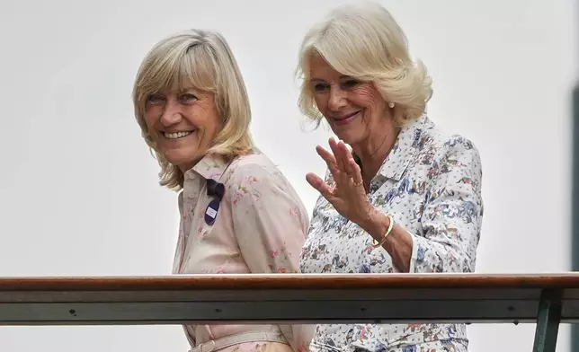 Britain's Queen Camilla waves as she walks to Centre Court accompanied by Deborah Jevans of the AELTC on day ten at the Wimbledon Tennis Championships in London, Wednesday, July 9, 2025. (AP Photo/Joanna Chan)