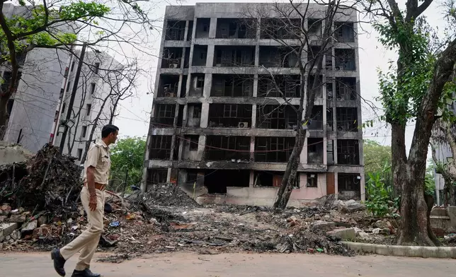 A policeman walks past buildings damaged in the June 12 Air India plane crash in Ahmedabad, India, Saturday, July 12, 2025. (AP Photo/Ajit Solanki)