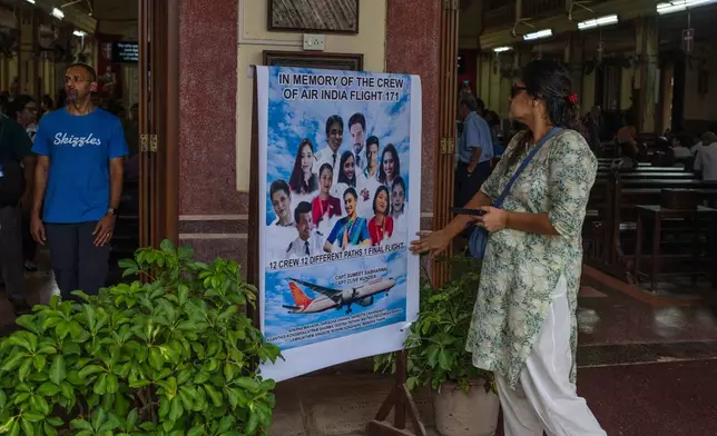 A woman offers tribute to the crew members of the Air India flight that crashed in Ahmedabad last month during a prayer meeting at a church in Mumbai, India, Saturday, July 12, 2025. (AP Photo/ Rafiq Maqbool)