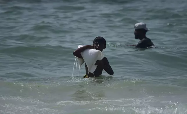 A Palestinian youth carries a sack of aid that landed in the Mediterranean Sea after being airdropped over central Gaza, at the shore of Zawaida, Gaza Strip Tuesday, July 29, 2025. (AP Photo/Abdel Kareem Hana)