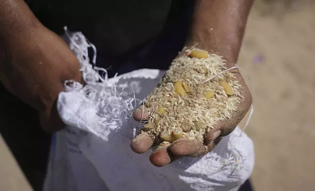 A Palestinian man displays the contents of humanitarian aid packages after they were airdropped into Zawaida, in the central Gaza Strip, Wednesday, July 30, 2025. (AP Photo/Abdel Karim Hanna)