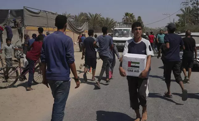 Palestinians collect humanitarian aid packages from the United Arab Emirates after they were airdropped into Zawaida, in the central Gaza Strip, Wednesday, July 30, 2025. (AP Photo/Abdel Kareem Hana)